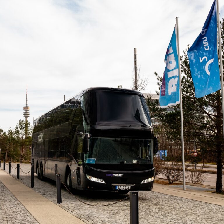 Schwarzer doppelstöckiger Reisebus von Transmobility steht vor dem O2-Gebäude in München