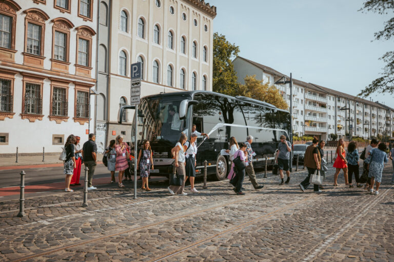 Touristen steigen aus einem schwarzen Reisebus der "Meet Germany Rhein-Main Tour" auf einem mit Kopfstein gepflasterten Platz in Deutschland aus